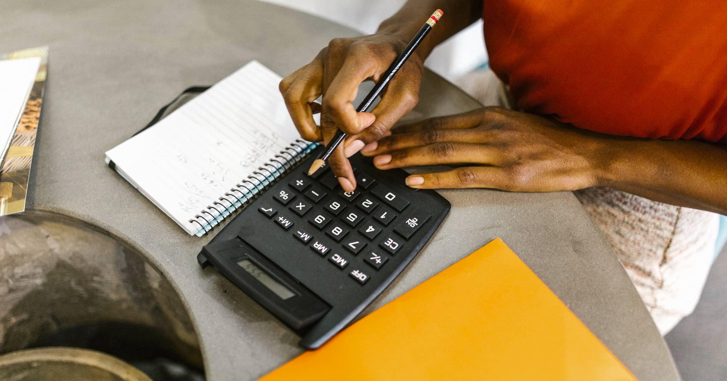 Hands using a calculator on a desk
